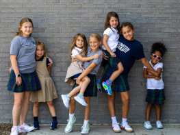 A group of 4th grade students stand with their Kindergarten buddies