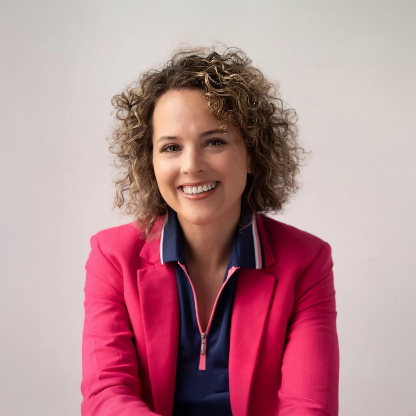 Smiling woman in pink blazer takes a headshot