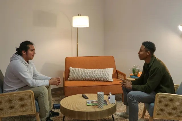 A high school student and an adult sit across from one another in a cozy conference room