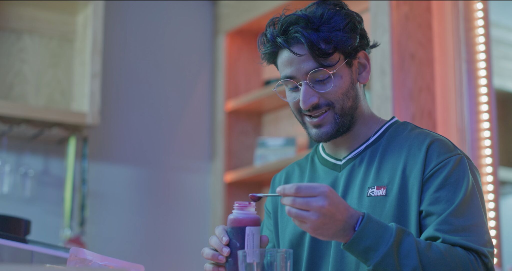 Young man in green sweatshirt measures red liquid
